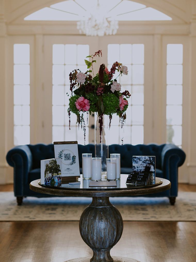 Elevated arrangement on a tall stand in a chandeliered foyer