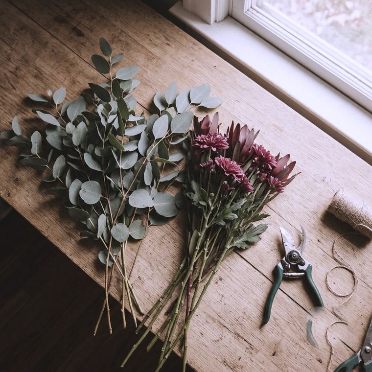 Eucalyptus and burgundy stems laid out on a work bench