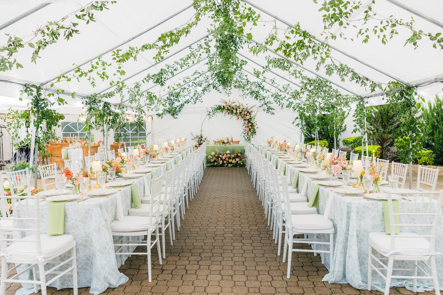 Tented banquet seating under a suspended greenery installation